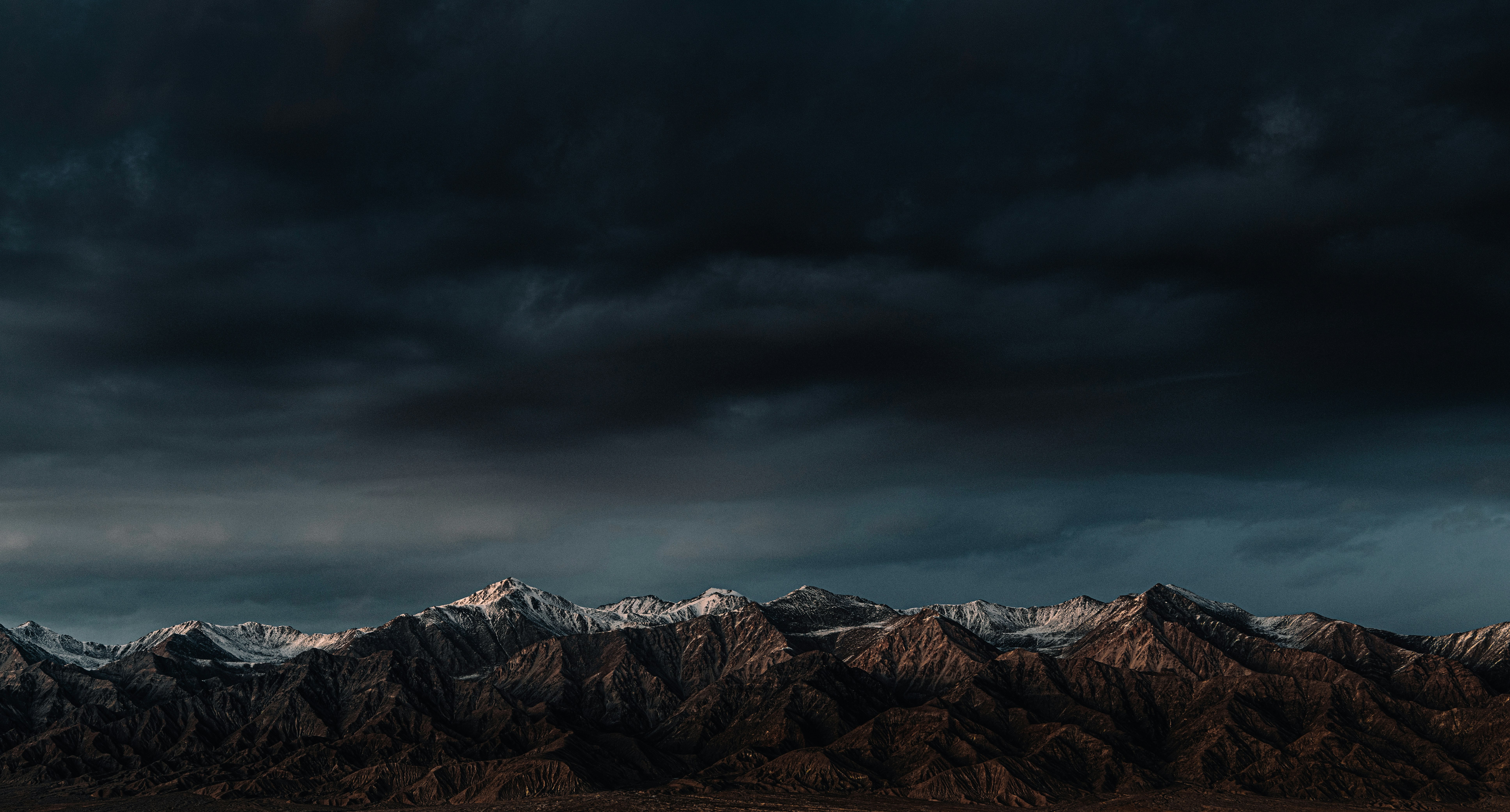 brown and white mountains under gray clouds